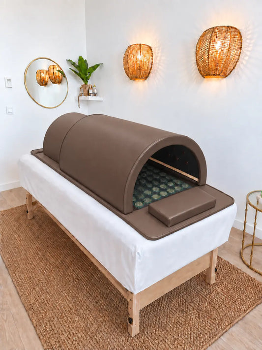 Sauna japonais infrarouge Haruki Dôme marron chocolat posé sur une table de soin, ouvert sur le tapis de pierres de jade